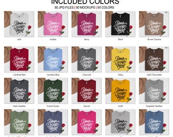 Puede incluir: Una colección de maquetas de camisetas en varios colores, incluyendo Ash, Azalea, Berry, Black y Brown Savana. Cada camiseta muestra el texto "Your Design Here", una rosa roja y un sombrero. La imagen presenta 50 colores.