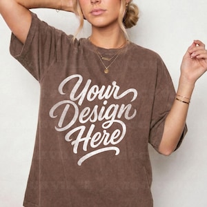 以下が含まれることがあります： 胸元に筆記体で白い文字「Your Design Here」がプリントされた、茶色の半袖クルーネックTシャツ。この衣類は、色あせたヴィンテージ風の質感で、ゆったりとしたリラックス感のあるフィット感が特徴です。