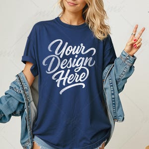 May include: Navy blue t-shirt with the text "Your Design Here" in a white script font. The model is wearing a light blue denim jacket. The image is a product mockup for apparel.