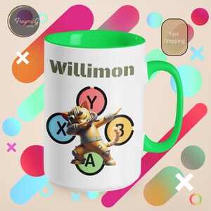 May include: White ceramic mug with a green rim and handle. The mug has a cartoon cat wearing a helmet and holding a video game controller. The text "Willimon" is printed on the mug.
