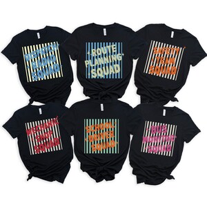 May include: Six black t-shirts featuring square graphics with vertical stripes and text. The shirts read: DISPATCH RADIO SQUAD, ROUTE PLANNING SQUAD, SAFETY TEAM SQUAD, MECHANIC SHOP SQUAD, SCHOOL DRIVER SQUAD, and BUS MONITOR SQUAD in various colors.