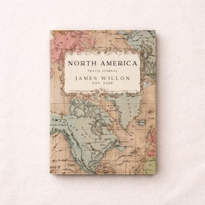 May include: A travel journal featuring a vintage map of North America. The cover has a cream-colored label with the text "NORTH AMERICA TRAVEL JOURNAL JAMES WILLON EST. 2020". The map is in shades of blue, pink, and beige, with a grid pattern.