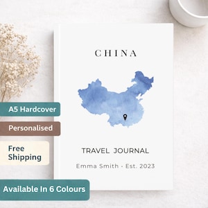 Puede incluir: Un diario de viaje A5 de tapa dura blanca con la palabra "CHINA" impresa en la parte superior. En el centro hay un mapa de China en acuarela azul. Las palabras "TRAVEL JOURNAL" y el nombre "Emma Smith" están impresos debajo. Disponible en 6 colores.