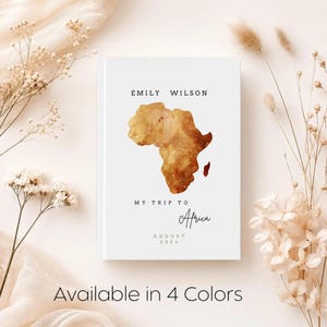 May include: A white journal with the text "Emily Wilson" and "My Trip to Africa" with a watercolor map of Africa. The date "August 2024" is also included. The words "Available in 4 Colors" are at the bottom.