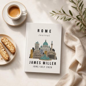 May include: A white "ROME Journal" with a colourful illustration of Roman landmarks. The journal is personalised with the name "JAMES MILLER" and the date "JUNE/JULY 2026". A cup of coffee and biscotti are in the background.