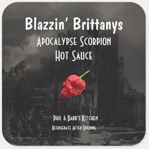 May include: A black and white image of a city skyline with a red chili pepper in the foreground. The text "Blazzin' Brittanys Apocalypse Scorpion Hot Sauce" is at the top of the image. The text "Phil & Barb's Kitchen" and "Refrigerate After Opening" are at the bottom of the image.