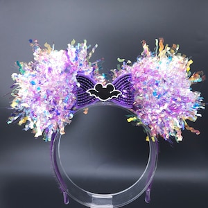 May include: Purple headband with iridescent purple and white pom-poms and a purple bow with a white bat and Mickey Mouse silhouette.