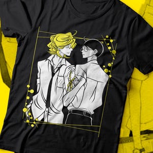 Könnte beinhalten: Schwarzes T-Shirt mit einem grafischen Druck von zwei Männern in Schwarzweiß. Die Männer stehen nah beieinander und einer hält ein gelbes Band. Der Hintergrund ist gelb.