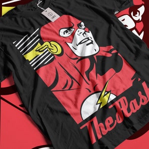 May include: Black t-shirt with a red and yellow illustration of The Flash, a superhero with lightning bolts. The text "The Flash" is written in red and yellow letters.