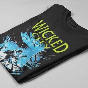 May include: Black t-shirt with a graphic print of a blue and white image with the text "WICKED CITY" in yellow.