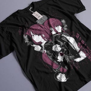 Op de afbeelding: Een zwart t-shirt met korte mouwen en een grafische print van twee anime-stijl personages met magentakleurig haar, waarvan er één rookt, en Japanse tekst. Een wit label met 'LARGE' is aan de kraag bevestigd met donkere lijnen en schaduwen.