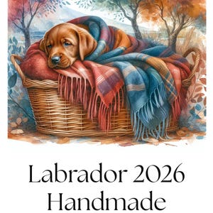 May include: Watercolor illustration of a Labrador puppy nestled in a woven basket, wrapped in a colorful blanket. The image has a soft, artistic style with text that reads "Labrador 2026 Handmade Calendar".