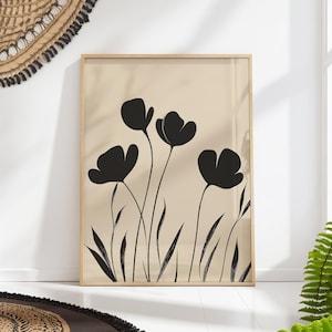 Peut inclure: Une impression d'art minimaliste en noir et blanc représentant des fleurs noires stylisées sur un fond beige. L'impression est encadrée dans un cadre en bois clair.