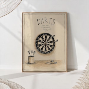 Könnte beinhalten: Ein gerahmter Wandkunstdruck mit einer Skizze einer Dartscheibe, in der zwei Darts stecken. Unter der Scheibe steht ein Behälter mit drei Darts, zwei weitere liegen auf der Fläche. Der Text lautet DARTS, good aim, clear mind, steady hand.