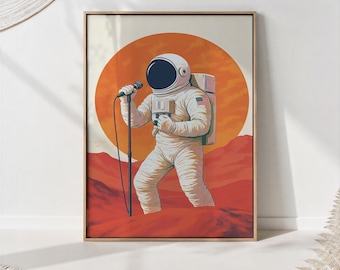 May include: A framed wall art print featuring an astronaut in a white spacesuit with a United States flag patch, standing on a red planetary surface. The astronaut holds a black microphone on a stand against a large, vibrant orange circular sun.
