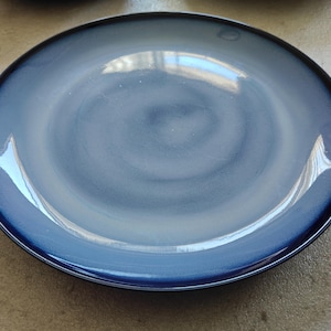 May include: A blue and white ceramic dinner plate with a swirl design. The plate has a glossy finish.