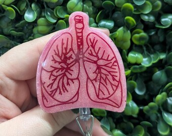 May include: Pink plastic badge reel with a detailed anatomical illustration of human lungs. The reel has a clear plastic retractable cord.