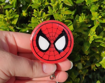 May include: A red and black Spider-Man themed retractable badge holder with a clear plastic strap and a silver metal clip.