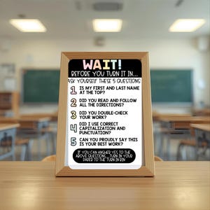 May include: A wooden framed sign with the text "WAIT! Before you turn it in... Ask yourself these 5 questions:" The sign is on a wooden desk in a classroom setting. The text includes a list of questions to review before submitting work.