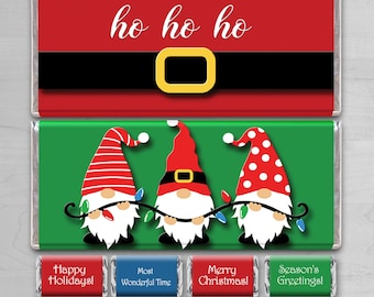 Puede incluir: Diez diseños para envoltorios de barras de chocolate de Navidad imprimibles con tres gnomos sosteniendo una cadena de luces. Los envoltorios tienen un esquema de color rojo y verde con el texto "ho ho ho" y "¡Felices Fiestas!"  "El mejor momento" "¡Feliz Navidad!" y "¡Saludos de la temporada!"