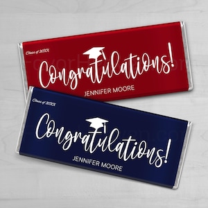 May include: Two chocolate bars, one red and one navy blue, with white text. The text reads "Congratulations!" with a graduation cap icon and a name. The top bar says "Class of 20XX".