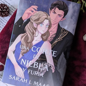 Può includere: Una copertina di libro con sfondo blu e nero che presenta una coppia. La donna ha lunghi capelli biondi e occhi azzurri. L'uomo ha i capelli neri e gli occhi azzurri. Il titolo del libro è "Una Corte de Niebla y Furia" di Sarah J. Maas.