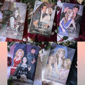 Puede incluir: Una colección de cinco libros de bolsillo con portadas coloridas que presentan ilustraciones de personas y criaturas fantásticas. Los títulos de los libros son "Una Corte de Espinas y Rosas", "Una Corte de Niebla y Furia", "Una Corte de Alas y Ruina", "Una Corte de Hielo y Estrellas", y "Una Corte de Llamas Plateadas".