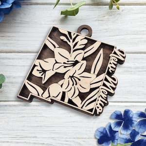 May include: Wooden ornament shaped like the state of New Mexico with a floral design and the words "New Mexico" on the side.