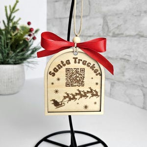 May include: Wooden Christmas ornament with a red bow and the text "Santa Tracker" with a QR code and a silhouette of Santa's sleigh with reindeer.