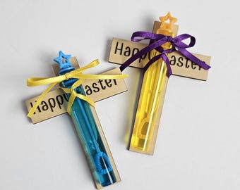 May include: Two wooden cross-shaped bubble wands with yellow and blue bubble solution. The crosses are decorated with yellow and purple ribbons and the text "Happy Easter".