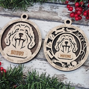 May include: Two wooden Christmas decorations featuring a dog breed silhouette with the words "Buddy" and "Maxine" on the nameplates. The decorations are decorated with words describing dog traits, such as "Loyal", "Friendly", and "Warm".