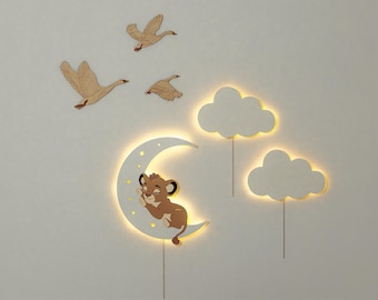 May include: A white wooden wall decor set with a crescent moon, clouds, and geese. The moon has a sleeping lion cub on it. The clouds and moon have warm white lights.