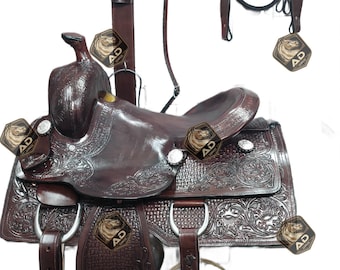 May include: A complete brown leather western saddle set. The set includes a saddle, bridle, breast collar, and other accessories. The saddle features intricate floral tooling and silver accents. This equestrian equipment is designed for riding and performance.