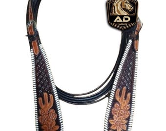 May include: A brown and black leather horse bridle with floral and geometric tooling. The bridle features white stitching and a decorative headstall. The logo "AD Saddler" is visible.