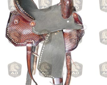 May include: A brown leather western saddle with intricate tooling and a dark gray seat. The saddle features stirrups, a horn, and a high cantle. The leather is a rich, warm brown with detailed stitching.