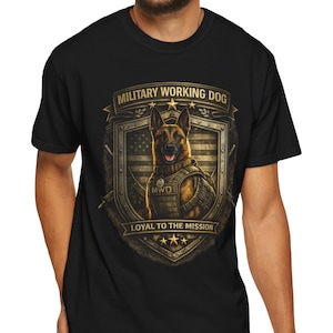 May include: Black t-shirt featuring a detailed graphic of a German Shepherd dog in military gear. The design includes the text "MILITARY WORKING DOG" and "LOYAL TO THE MISSION" with an American flag background, creating a patriotic theme.