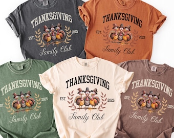 May include: A collection of five short-sleeved t-shirts in various colors: charcoal, orange, green, cream, and brown. Each shirt features the word "THANKSGIVING" above a turkey graphic and the text "Family Club" below, with "EST. 2025".