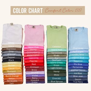 以下が含まれることがあります： さまざまな色のComfort Color 1717 Tシャツが並んだカラーチャート。白、ピンク、緑、青などの色が、それぞれの名前とともに表示されています。「カラーチャート」の文字が上部にあります。