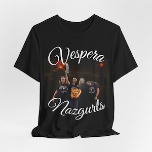 Pode incluir: T-shirt preto com a inscrição "Vespera Nazgurls" em uma escrita estilizada. A imagem na camiseta mostra um grupo de pessoas segurando objetos em frente a um fundo escuro e ardente.