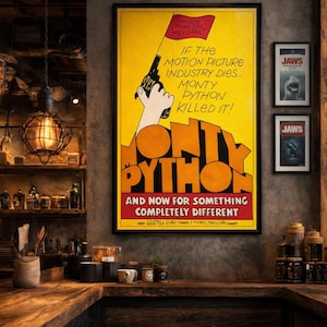 May include: A framed Monty Python poster with a yellow background and the text "If the motion picture industry dies... Monty Python killed it!" A hand holding a gun is depicted. Two "Jaws" movie posters are also visible.