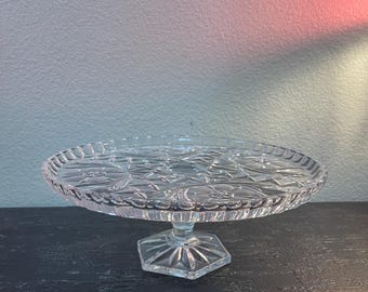vintage crystal footed cake stand featuring a pressed starburst pattern and a hexagonal base.