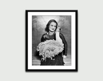 Può includere: Una fotografia in bianco e nero di una donna che tiene un grande oca bianca. La donna indossa un vestito scuro e una collana. L'oca sta guardando la fotocamera.