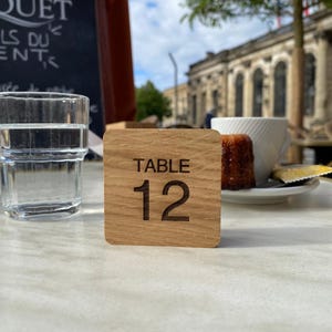May include: A wooden table number with the text "TABLE 12" engraved on it.