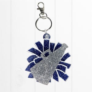 May include: A silver glitter megaphone and blue pom-pom keychain with a silver clasp and key ring. The keychain is designed with a cheerleading theme, perfect for fans of the sport.
