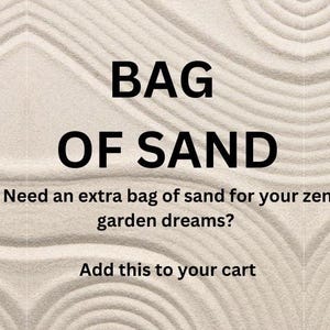 May include: A close-up of white sand with a zen garden design. The text "BAG OF SAND" is written in black letters. The text "Need an extra bag of sand for your zen garden dreams? Add this to your cart" is also written in black letters.