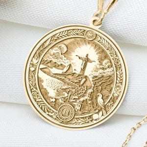 May include: A gold pendant necklace with a round, detailed medallion featuring a scene of a bird in flight. The medallion is surrounded by a decorative border.