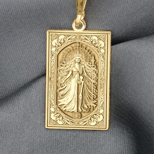 以下が含まれることがあります： 金色のペンダントネックレス。長方形のペンダントには、剣を持ったローブを着た人物の彫刻が施されています。ペンダントは繊細なチェーンから吊り下げられています。背景は灰色の生地です。