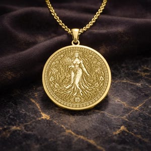 May include: A gold-toned circular pendant necklace featuring an embossed figure of a woman holding wheat stalks, surrounded by intricate floral patterns and the Roman numeral symbol for Virgo at the bottom, suspended from a matching gold chain.