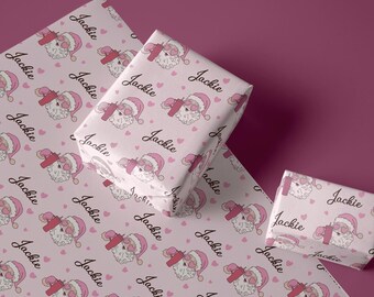 May include: Pink wrapping paper with a repeating pattern of Santa Claus wearing sunglasses and holding a drink. The name "Jackie" is repeated throughout the pattern.