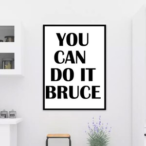 K&ouml;nnte beinhalten: Schwarz-wei&szlig;es Motivationsposter mit dem Text "YOU CAN DO IT BRUCE" in fetten Blockbuchstaben.